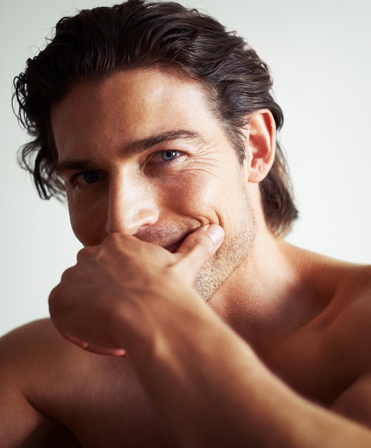 Man smiling with hand on chin, close-up.