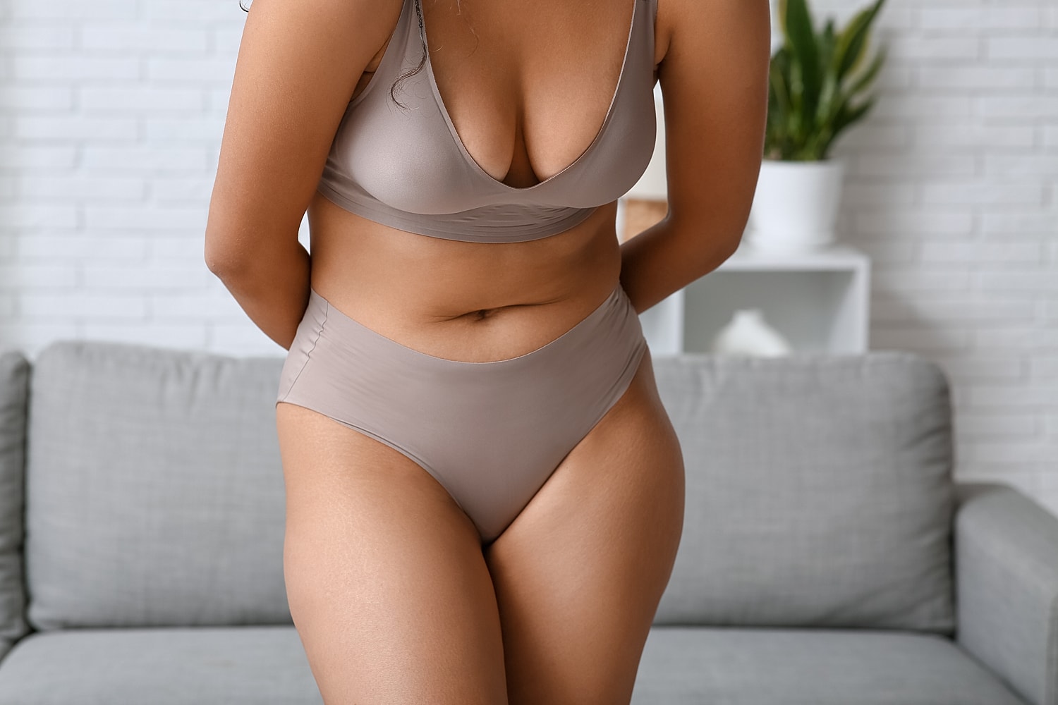 Model wearing neutral swimwear in cozy setting.