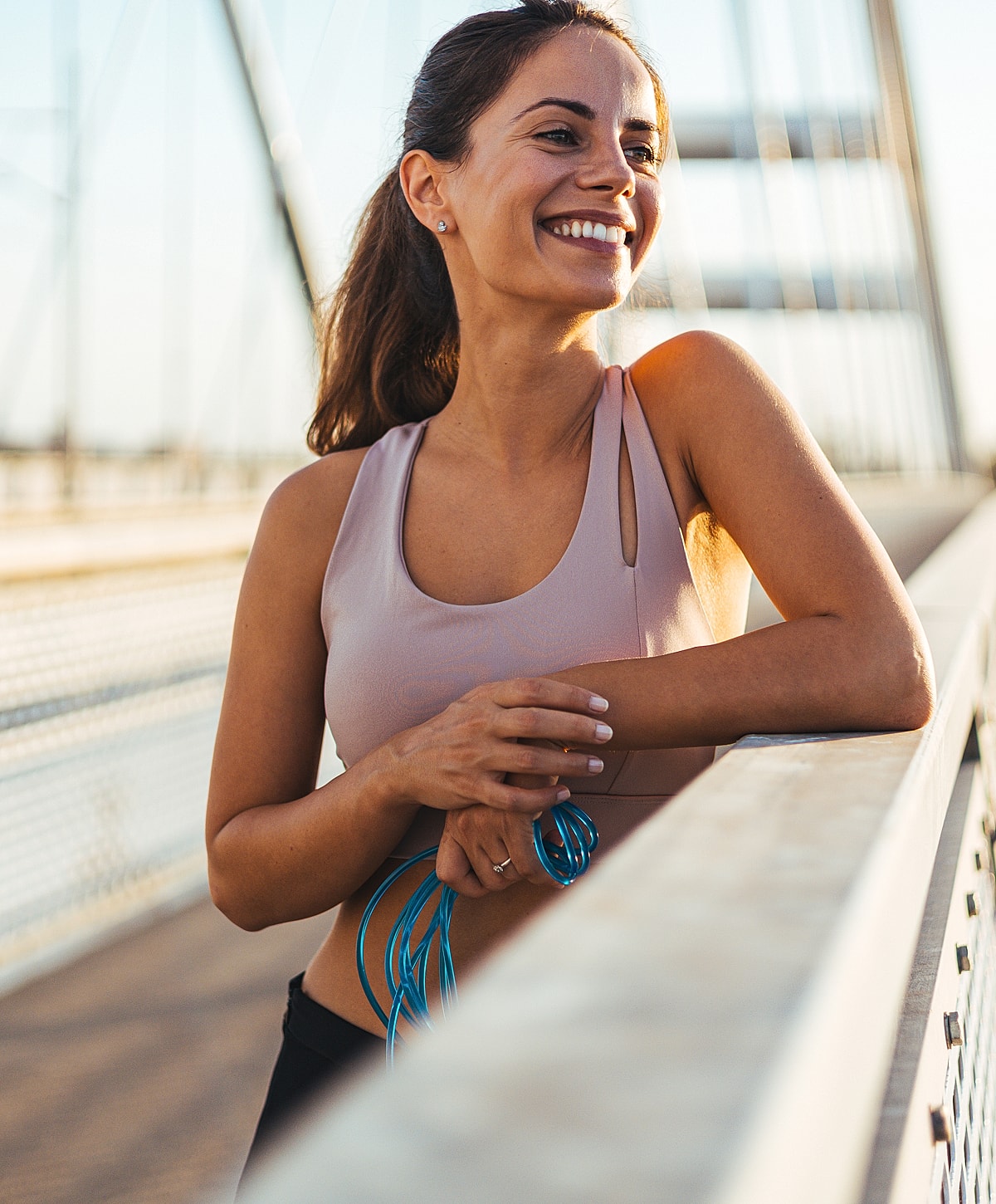 Smiling woman in workout gear on a bridge.