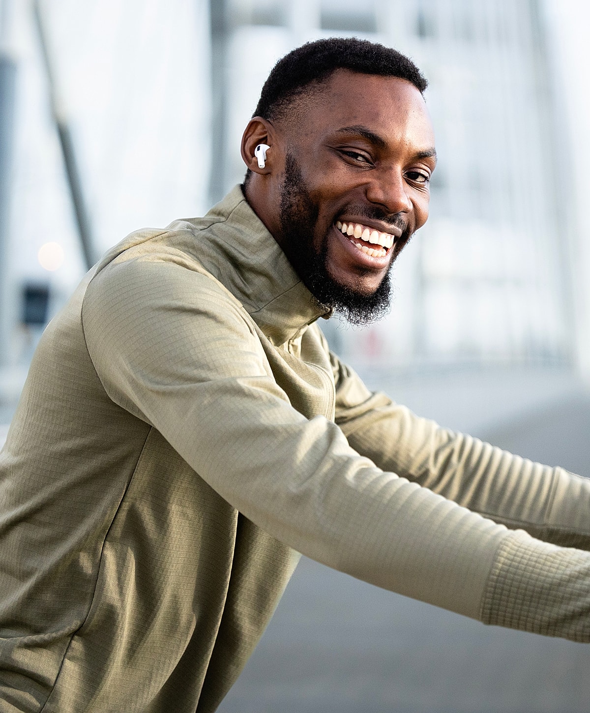 Smiling man wearing earphones outdoors.