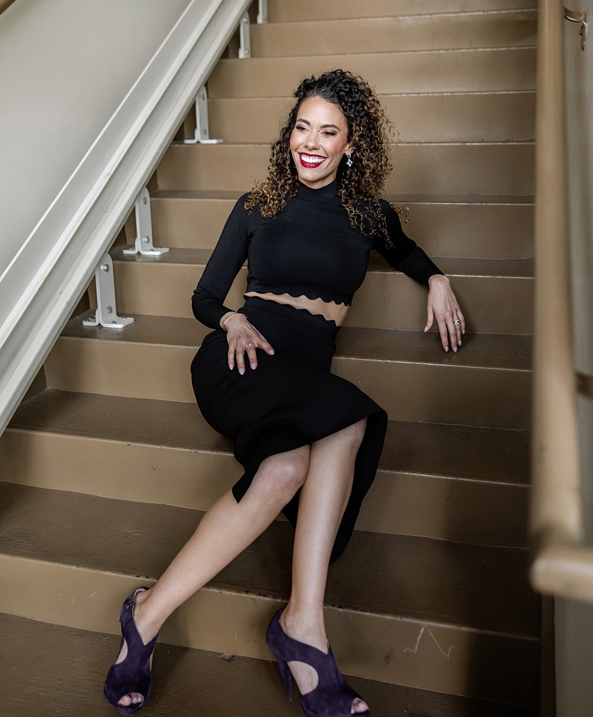 Woman in black outfit sitting on stairs.