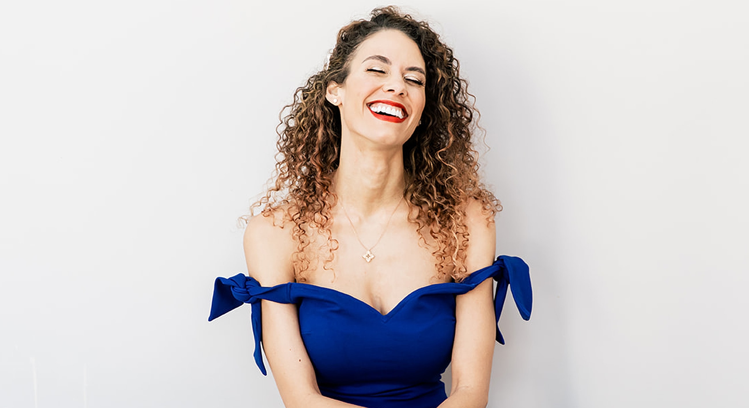 Woman smiling in a blue off-shoulder dress.