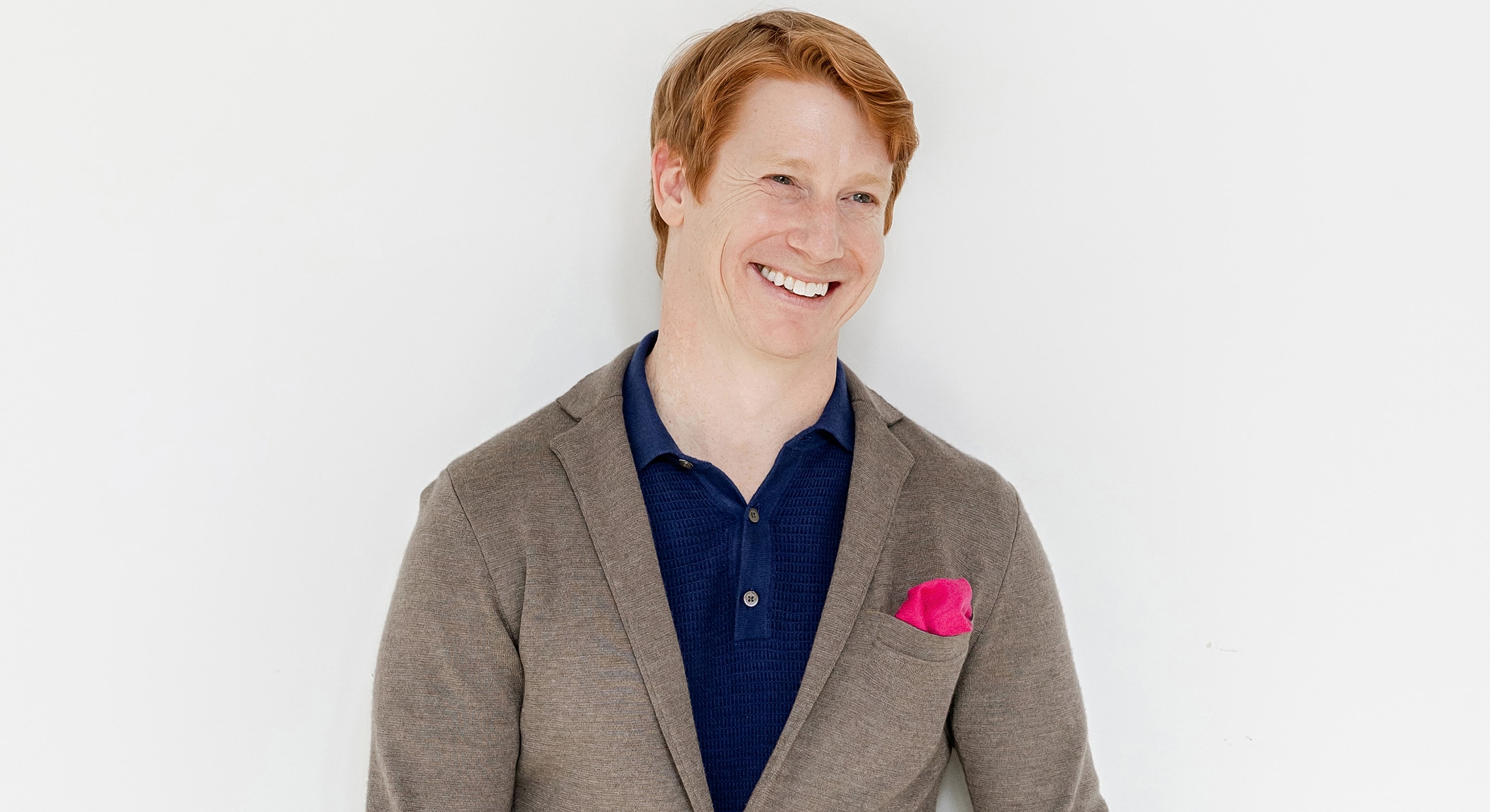 Smiling man in a blazer and polo shirt.