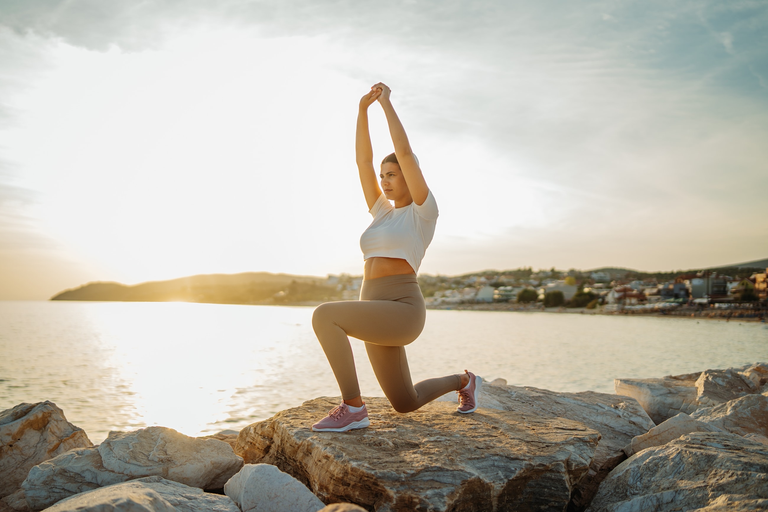 Woman stretching outdoors by the sea at sunset